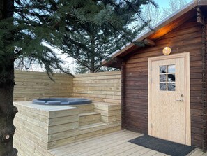 A wooden cabin with a hot tub and a door with a window. - Skard Cottages (Hrunamannahreppur)