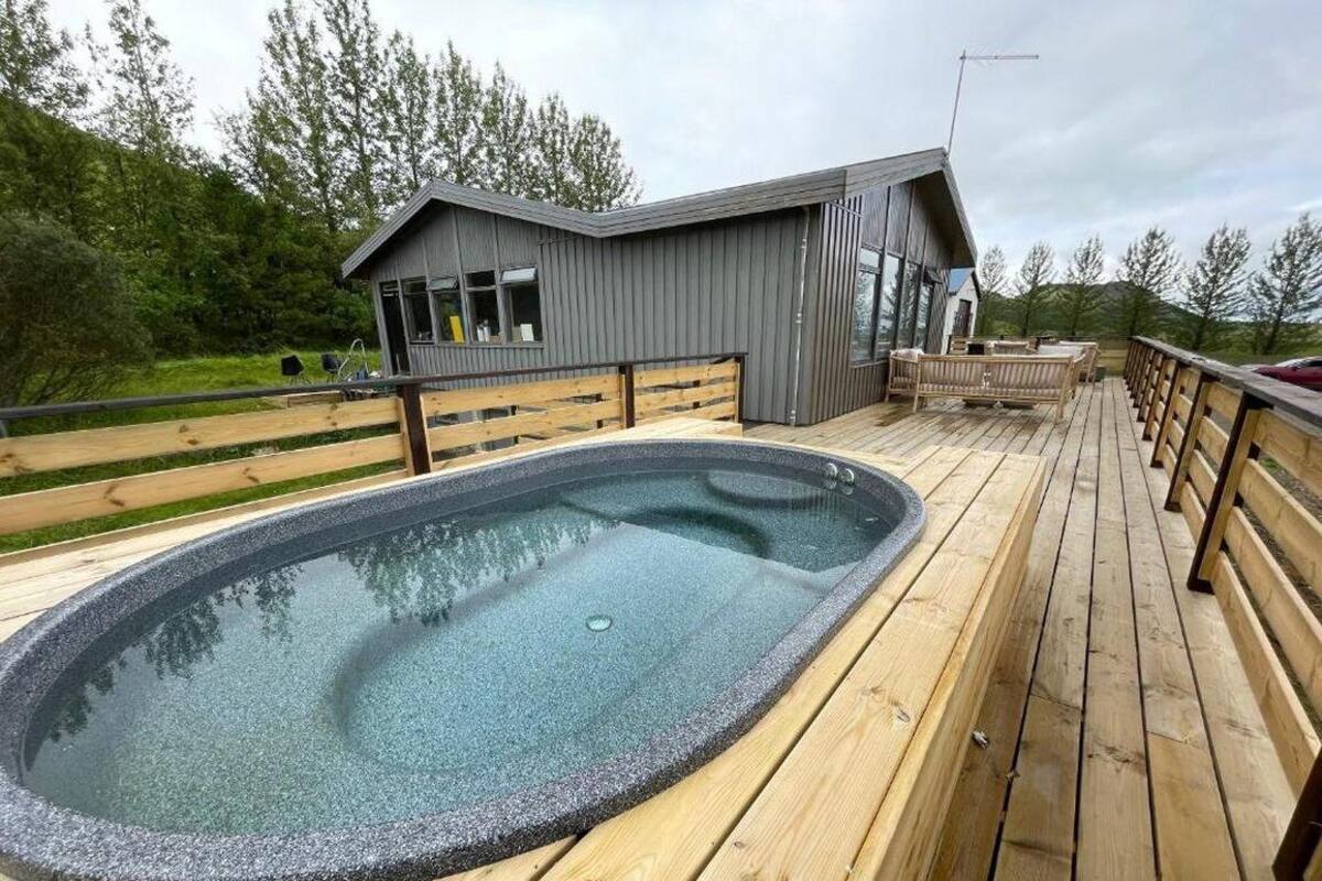 Une terrasse en bois avec un jacuzzi et un bâtiment moderne doté de grandes fenêtres.