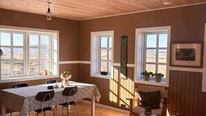Una habitación amplia con techo de madera, ventanas grandes, una mesa de comedor y una zona de estar acogedora con chimenea.