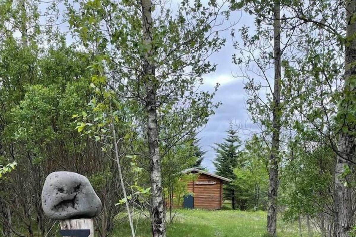 Un poteau en bois portant le numéro 3, un chalet en bois et un sentier bordé d’arbres.