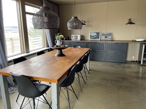 A modern kitchen with a wooden table, black chairs, and pendant lights. - Skard Cottages (Hrunamannahreppur)