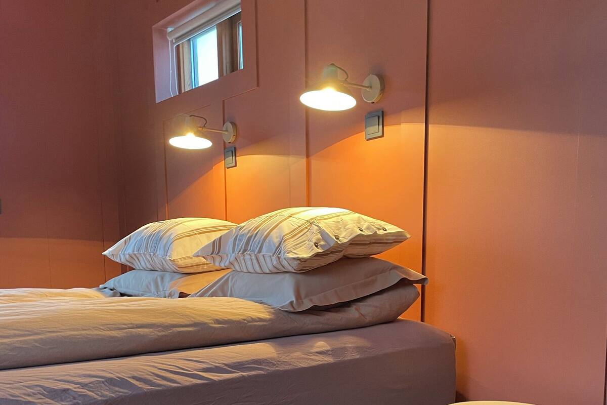 Une chambre à coucher avec un lit, des oreillers, une table de chevet et des lampes fixées au mur.