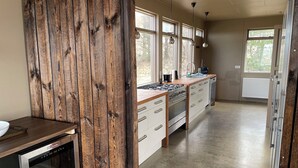 Una cocina con pared decorativa de madera, estufa a gas, gabinetes blancos y lavavajillas.