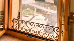 A view through a window with a metal railing, looking out onto a courtyard with a building in the background. - Le Finestre su Borghetto (Valeggio sul Mincio)