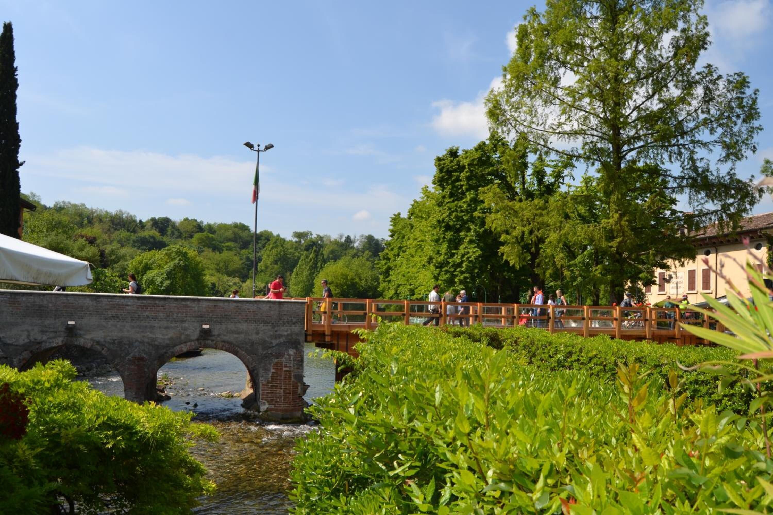 A stone bridge over a river with lush greenery and trees in the background.