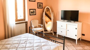 A bedroom with a bed, a dresser, a chair, a mirror, and a television. - Le Finestre su Borghetto (Valeggio sul Mincio)