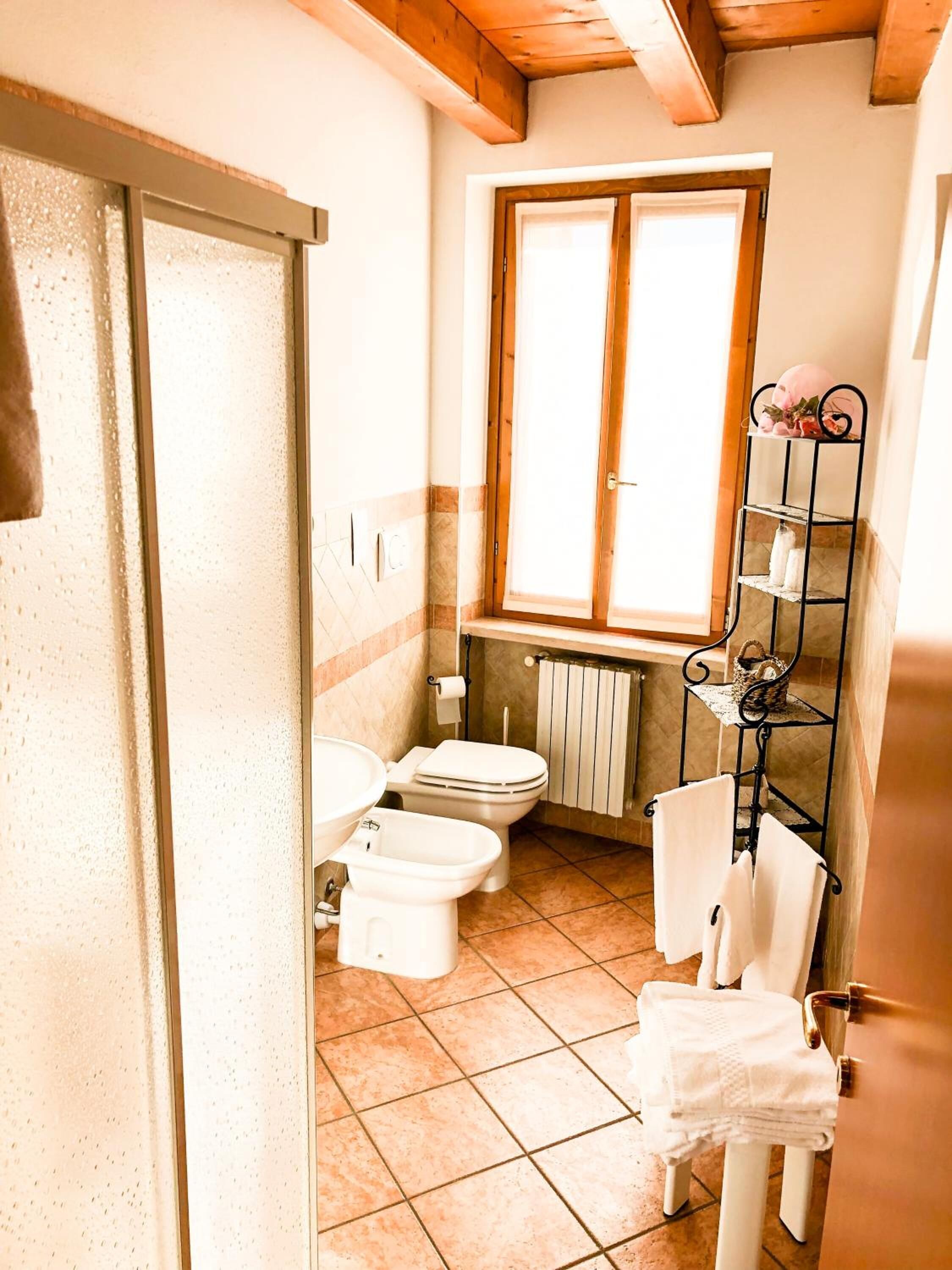 Ein kleines Badezimmer mit Toilette, Bidet und einem Fenster über dem Waschbecken.