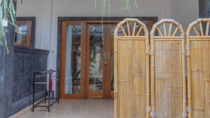 Un espace d’accueil doté d’une porte en bois, d’un paravent en bambou et d’un paillasson.