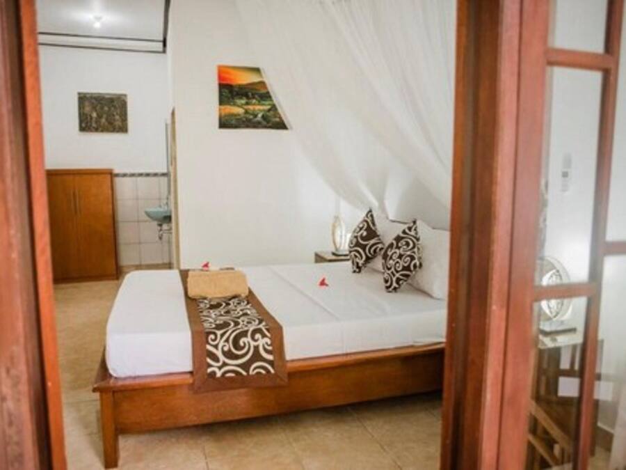A bedroom with a wooden bed, white bedding, a patterned throw, and two pillows.
