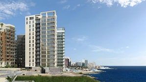A modern high-rise building with multiple balconies, situated near a coastline. - Super Luxury Apartment in Tigne Point, Amazing Ocean Views (Sliema)