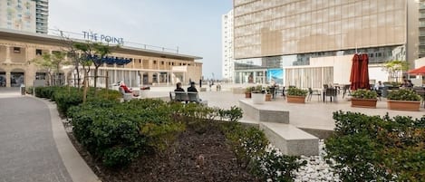A hotel with a modern facade, outdoor seating area, and a landscaped garden.