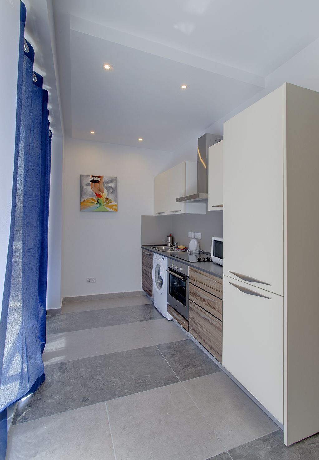 A compact kitchen with a washing machine, oven, and a microwave.
