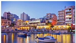 A waterfront cityscape with buildings, a prominent Dolce Vita restaurant, and several boats docked in the water. - Deluxe Studio in a Prime Location, Wifi (Sliema)