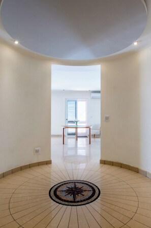A spacious room with a tiled floor, a central circular design, a table, and a door leading to another room. - Bright, Spacious and Right in the Center (St. Julian's)