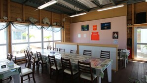 Un restaurante con paredes de madera, ventanas amplias y mesas con manteles florales.