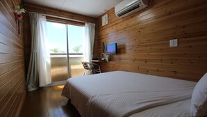 Una habitación con paneles de madera, una cama, un escritorio y un televisor.