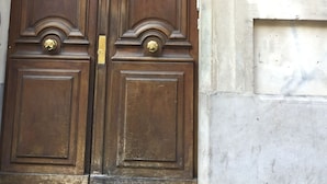 A large wooden double door with a brass handle and a decorative metal grille above it. - Liberté (Marseille)