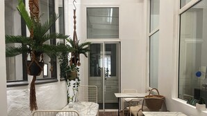 A cozy patio with two tables and chairs, a hanging plant, and a view of the street. - Liberté (Marseille)