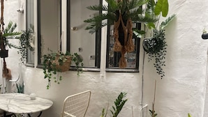 A room with a white wall, a window with a view, a white table with a chair, and several potted plants. - Liberté (Marseille)