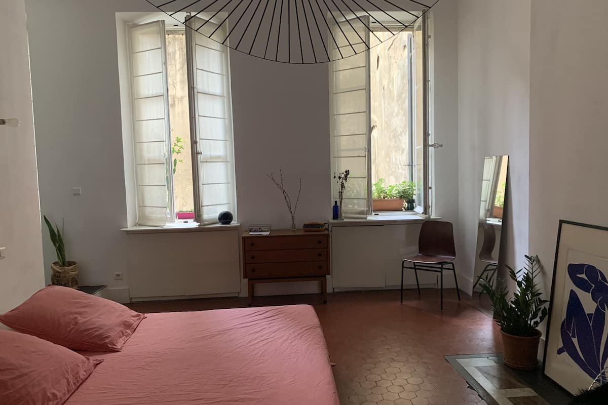 Une chambre à coucher avec un lit, un bureau, une chaise, une fenêtre et un miroir.