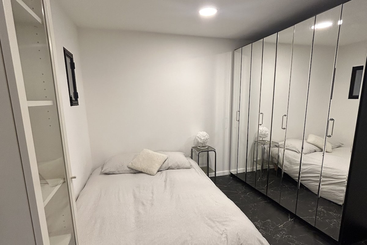 Une chambre à coucher avec un lit, une armoire, une petite table et un miroir.