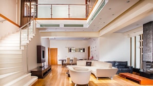 A spacious living area with a staircase, a fireplace, and a dining area. - Grand Villa Santorini (Santorini)