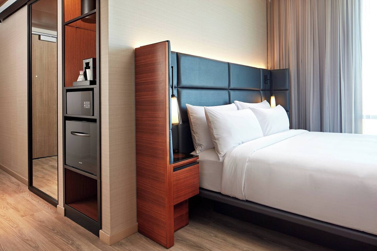 Ein Hotelzimmer mit einem Bett, einem Nachttisch, einem Einbauschrank und einem Beistelltisch.