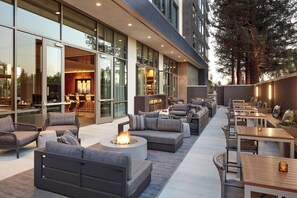 Een terras met buitenbanken, tafels en een vuurkorf.