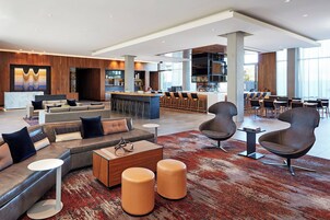 Un área de lounge moderna con bar, diferentes disposiciones de asientos y una recepción.
