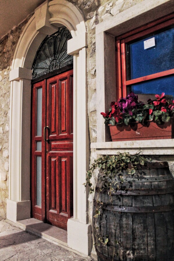 A stone building with a red door and a window with a blue frame. - Collis Petri Relais (Collepietro)