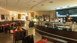 A restaurant with a bar area, booths, and tables with red tablecloths. - Hotel 4 Winden (Windhagen)