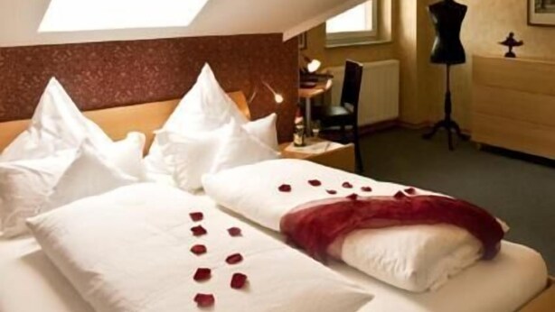 A hotel room with a bed, a chandelier, a desk, and a wardrobe. - Hotel 4 Winden (Windhagen)