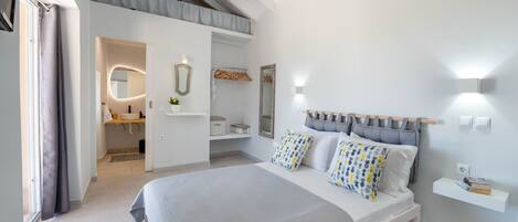 A modern bedroom with a large bed, a built-in bench, a vanity with a mirror, and a small shelf.