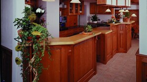 A kitchen with wooden cabinets, a central island, pendant lights, and potted plants. - Hotel und Gasthof Spessarttor (Lohr am Main)