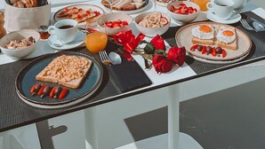 A table set with breakfast items overlooking a coastal cliff and the sea. - Echoes Luxury Suites (Santorini)
