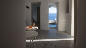 A modern interior with a view of the sea through an archway. - Echoes Luxury Suites (Santorini)