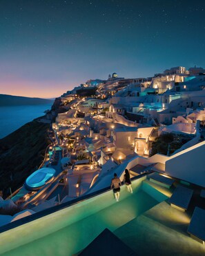 A coastal hotel with a swimming pool, a beach, and a view of the sea. - Echoes Luxury Suites (Santorini)
