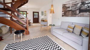 Una sala de estar moderna con una escalera, un sofá con cojines estampados y una fotografía grande en blanco y negro en la pared.