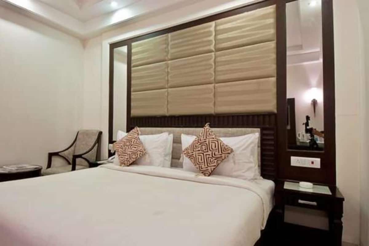Una habitación de hotel con una cama grande, una silla, una mesita de noche y un espejo.