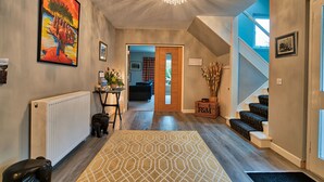 Un intérieur moderne avec un escalier, un radiateur, un tapis à motifs et un lustre.