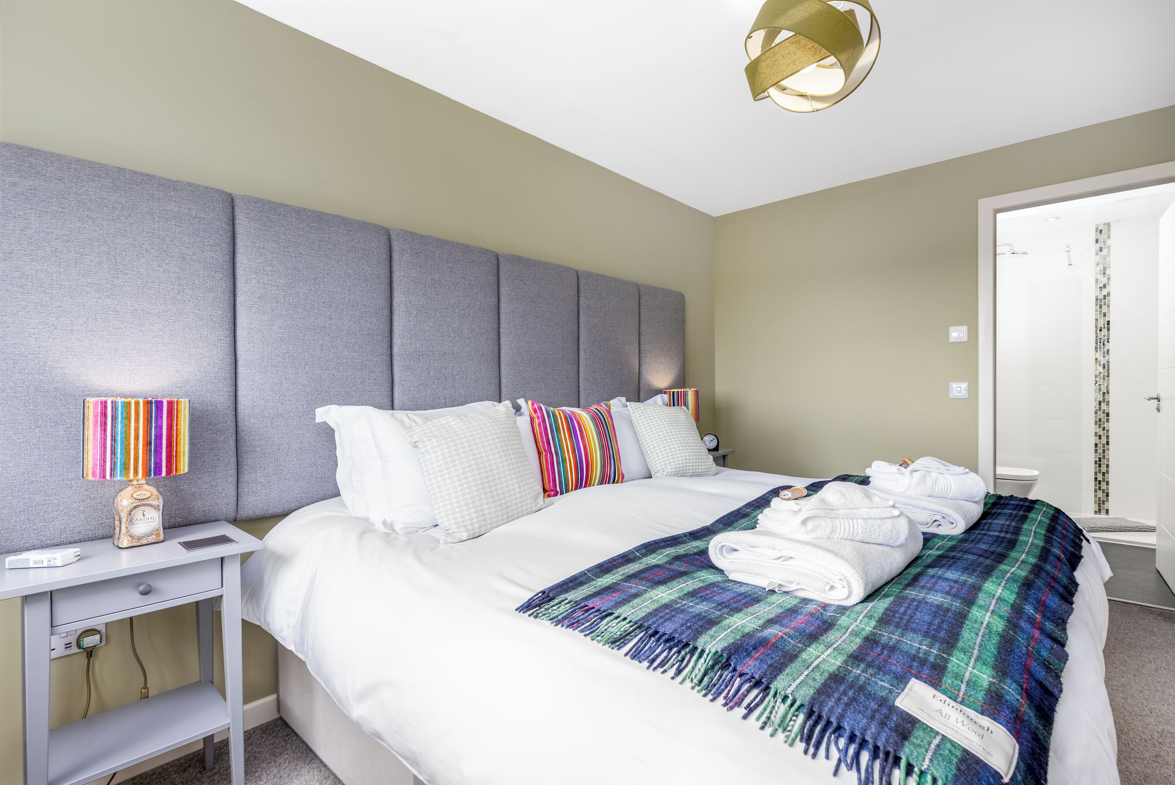 Een hotelkamer met een groot bed, een nachtkastje met een lamp en een douche.