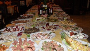 Ein langer Tisch mit verschiedenen Speisen und Weinflaschen, vermutlich für ein Buffet oder eine Veranstaltung aufgestellt.