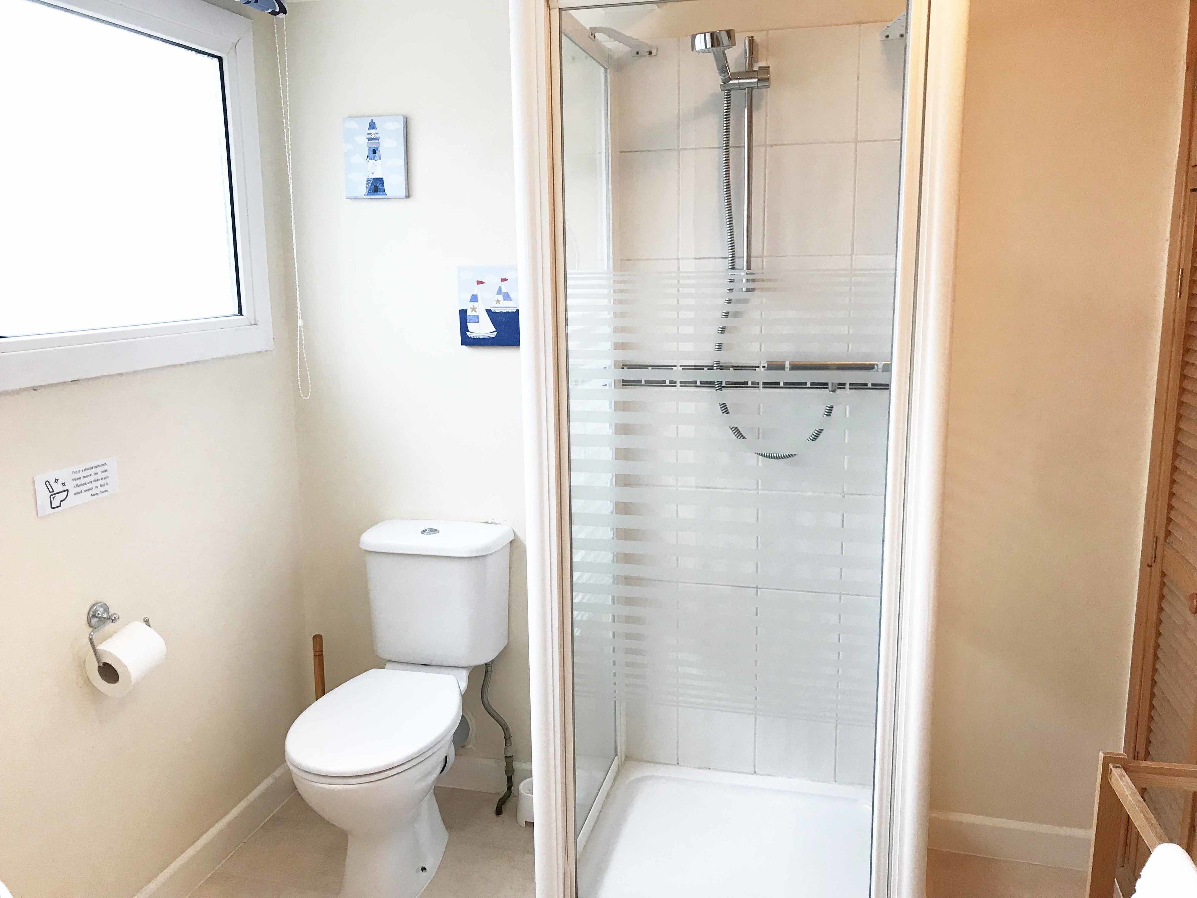 Une salle de bain avec des toilettes, une douche et une fenêtre.