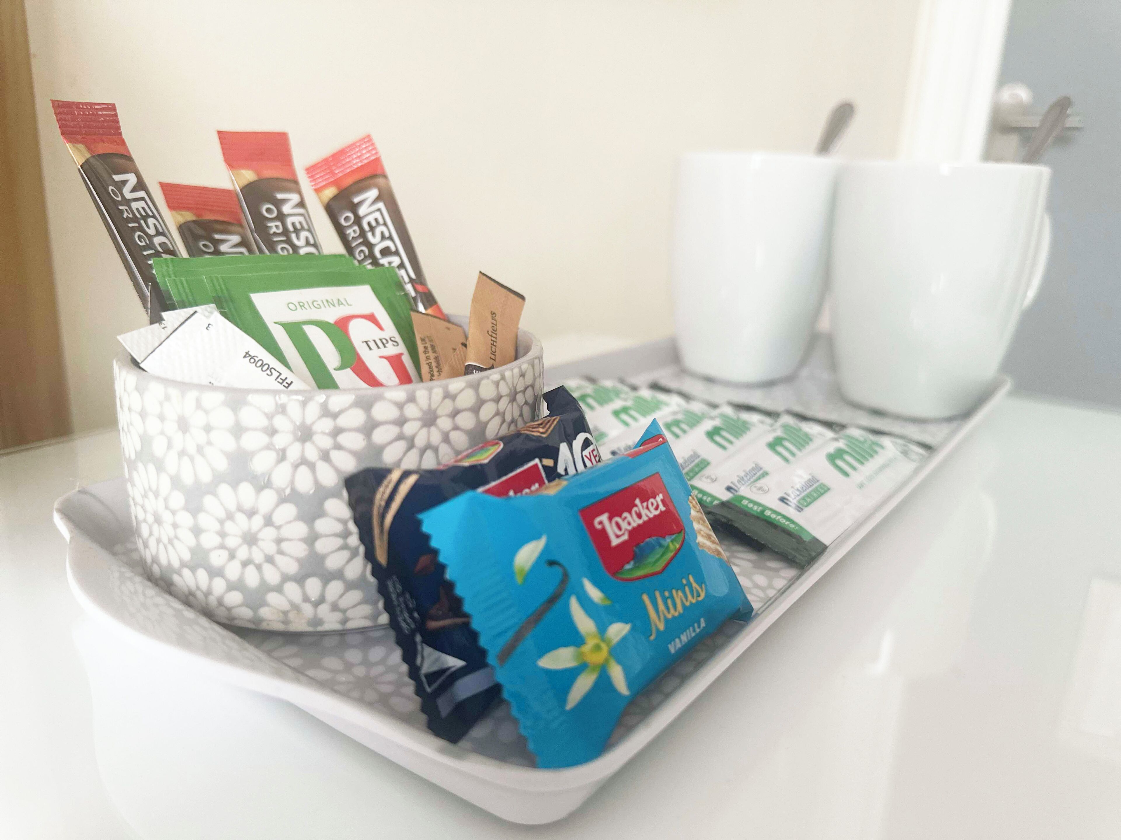 A tray with a cup of coffee, a pack of Toaster mini chocolate, and several Nestle Original coffee packets.