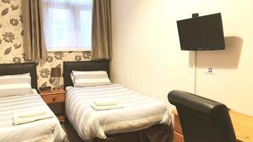 Una camera d'albergo con due letti, una TV a parete e una scrivania con una sedia.