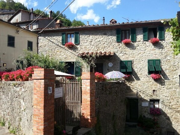 A stone building with green shutters, a gate, and potted flowers. - B&B La Margine con area benessere (Bagni di Lucca)