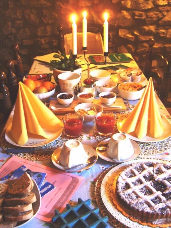 A table set for a meal with various dishes, including a pie, bowls, and a candle holder with candles. - B&B La Margine con area benessere (Bagni di Lucca)