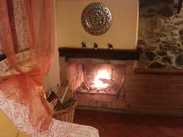 A room with a fireplace, a stone wall, and a bed with a patterned bedspread. - B&B La Margine con area benessere (Bagni di Lucca)