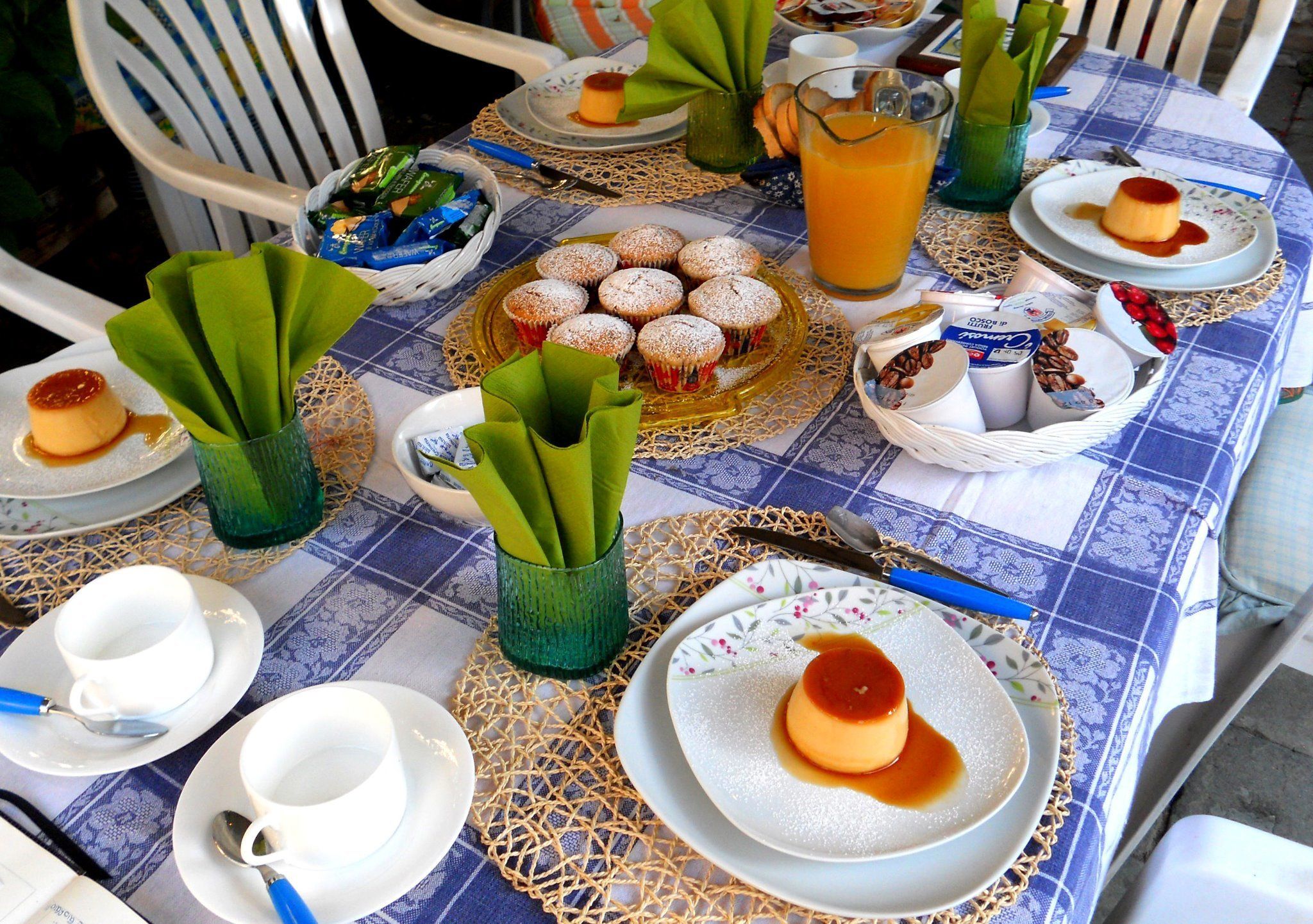 Uma mesa posta com doces, um jarro de sumo de laranja e diversos utensílios.