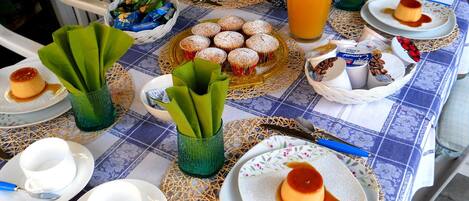 Uma mesa posta com doces, um jarro de sumo de laranja e diversos utensílios.